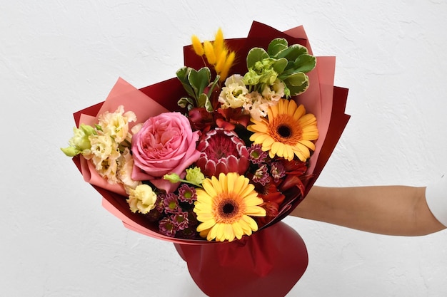 Hermosas flores para vacaciones Mujer con hermosas flores en las manos en el interior de fondo ramo de flores para floristería