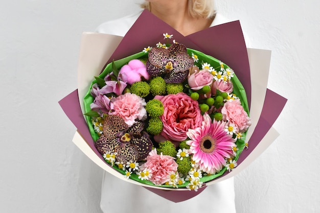 Hermosas flores para vacaciones Mujer con hermosas flores en las manos en el interior de fondo ramo de flores para floristería