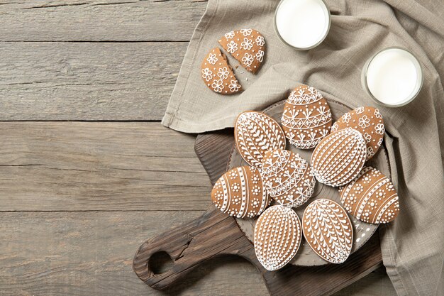 Hermosas galletas de pascua en un plato, un vaso de leche. Sobre fondo de madera vieja