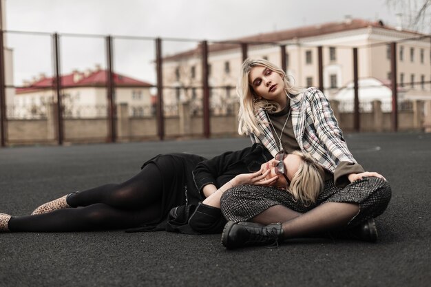 Hermosas hermanas gemelas de moda descansando en el patio de recreo