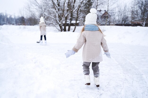 Hermosas hermanas jugando en tierra cubierta de nieve durante el invierno