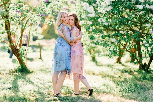 hermosas hermanas en vestidos posando en el parque de verano