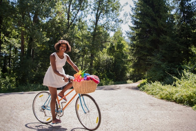 hermosas jóvenes afroamericanas disfrutan mientras montan en bicicleta en el bosque en un día soleado de verano