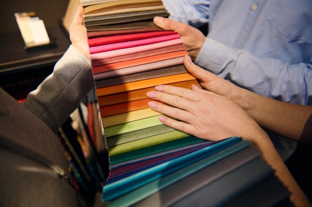 Foto hermosas manos femeninas bien arregladas en muestras de telas coloridas de varias calidades y texturas para tapicería de sofás diseño interior de mejoras para el hogar