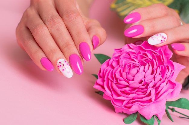 Hermosas manos femeninas con diseño de peonías de manicura rosa