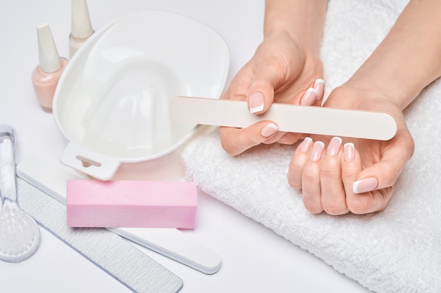 Hermosas manos femeninas con manicura francesa sobre superficie gris claro