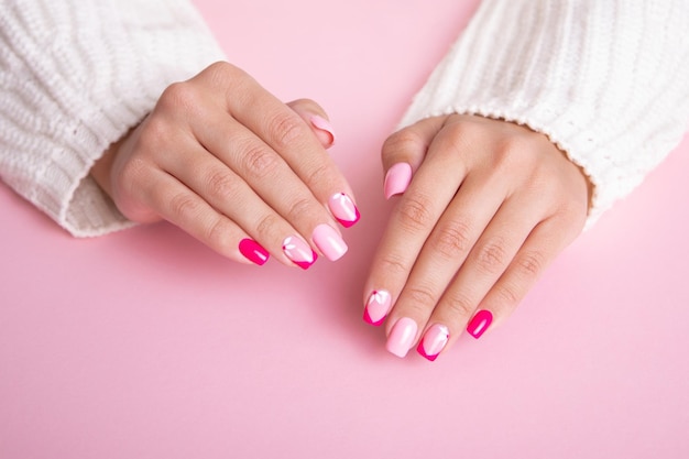 Foto hermosas manos femeninas con uñas de manicura de moda diseño de flores esmalte de gel rosa