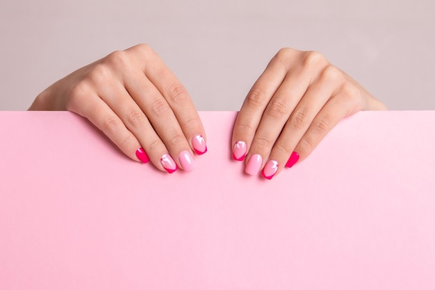 Foto hermosas manos femeninas con uñas de manicura de moda diseño de flores esmalte de gel rosa