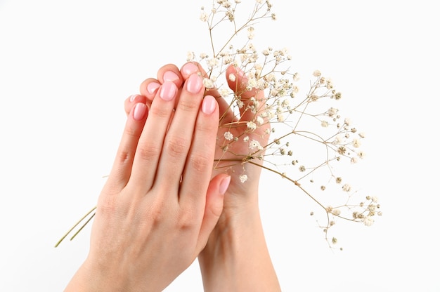 Hermosas manos femeninas con manicura en una pared aislada