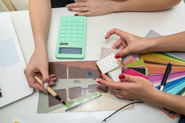 Hermosas manos femeninas con manicura trabajando con muestras de color para diseñar habitaciones en la mesa