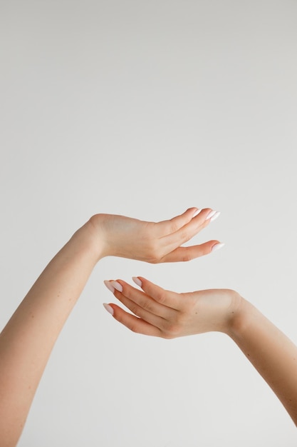 Hermosas manos femeninas sobre un fondo blanco.