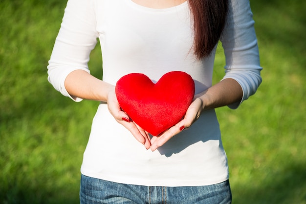 Hermosas manos de mujer asiática con corazón rojo suave