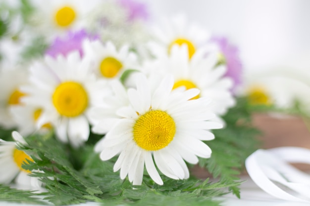 Hermosas margaritas y otras flores sobre una mesa blanca.