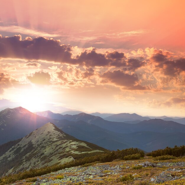 Hermosas montañas, puesta de sol, picos altos, nubes y luz solar roja