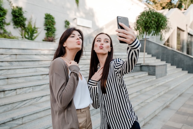 Hermosas mujeres casuales haciendo selfie al aire libre en la ciudad