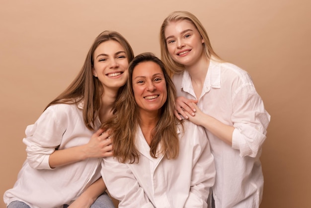 Hermosas mujeres caucásicas jóvenes con cabello rubio y camisas blancas sonríen a la cámara con fondo beige