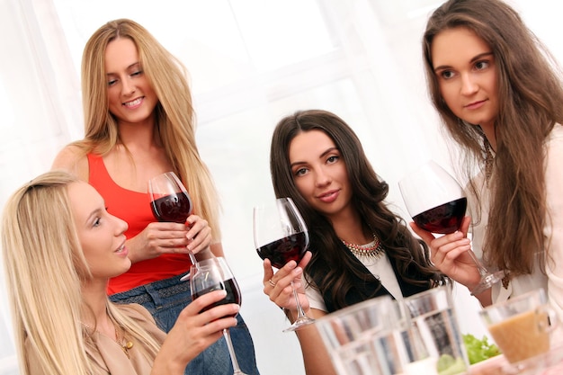 Hermosas mujeres caucásicas con vino tinto celebrando en casa