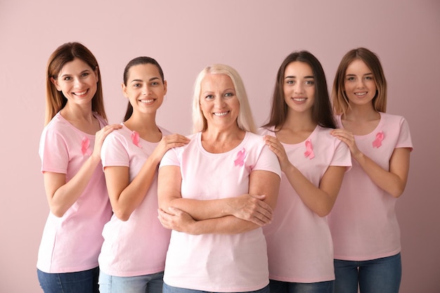 Hermosas mujeres de diferentes edades con cintas rosas sobre fondo de color Concepto de cáncer de mama