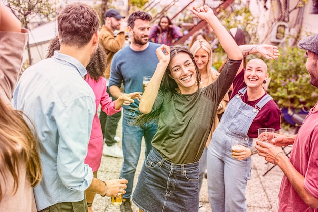 Hermosas mujeres y hombres bailando en una fiesta en una terraza al aire libre celebración de baile adultos jóvenes divirtiéndose sonriendo y riendo juntos