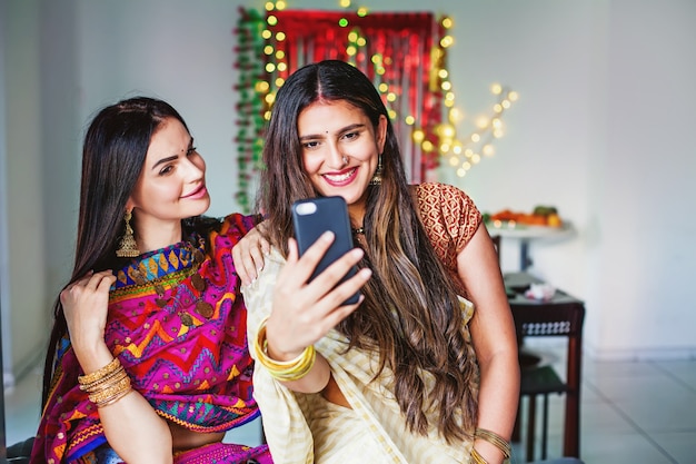 Hermosas mujeres indias tomando selfie en habitación decorada