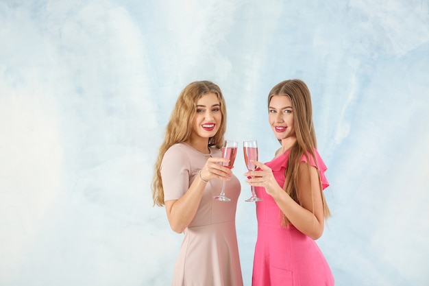 Foto hermosas mujeres jóvenes con copas de champán sobre fondo claro