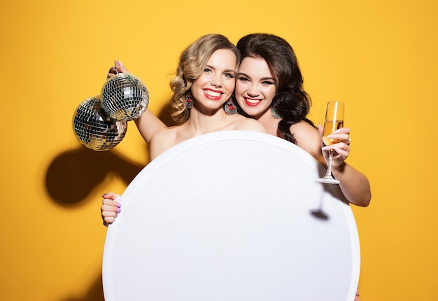 Foto hermosas mujeres jóvenes con copas de vino y bola de discoteca