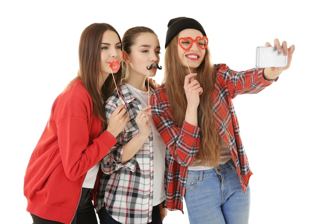 Foto hermosas mujeres jóvenes con decoración de fiesta tomando selfie sobre fondo blanco.