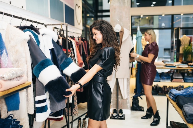 Hermosas mujeres jóvenes probando ropa elegante en boutiques o tiendas caras.