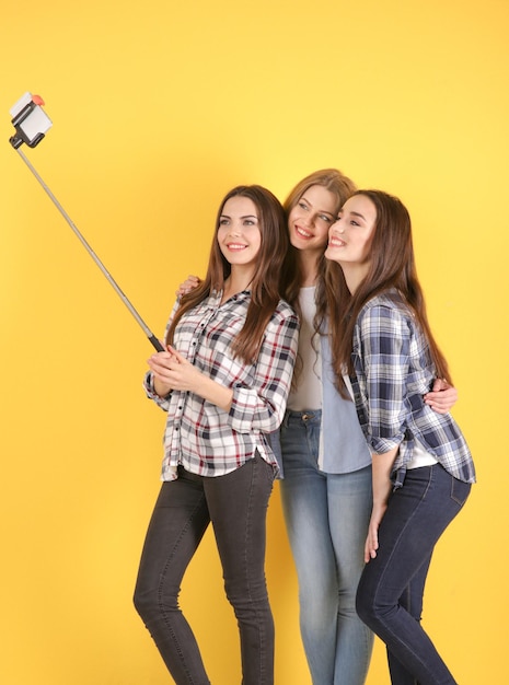 Foto hermosas mujeres jóvenes tomando selfie junto a la pared de color