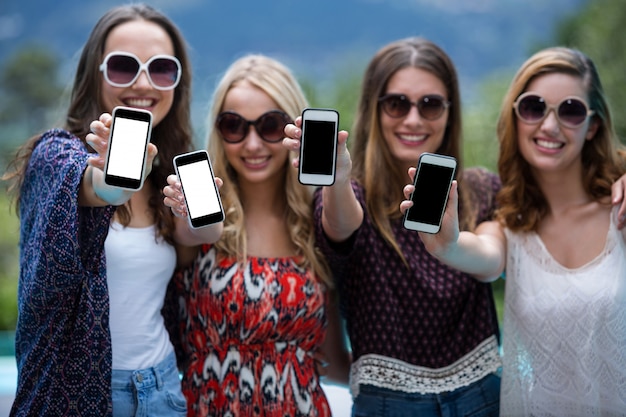 Hermosas mujeres mostrando sus teléfonos móviles