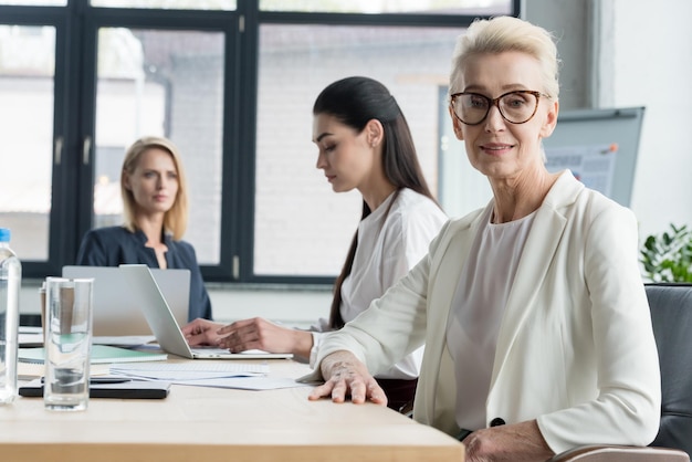 Foto hermosas mujeres de negocios sentadas en la mesa durante una reunión en la oficina