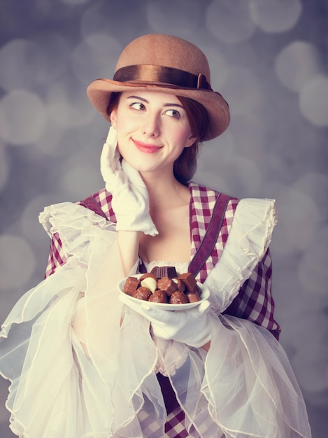 Hermosas mujeres pelirrojas con dulces. Foto de estilo retro con bokeh de fondo.