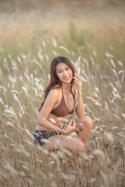 Hermosas mujeres rubias en bikini marrón en un prado marrón con flores blancas en las noches de verano