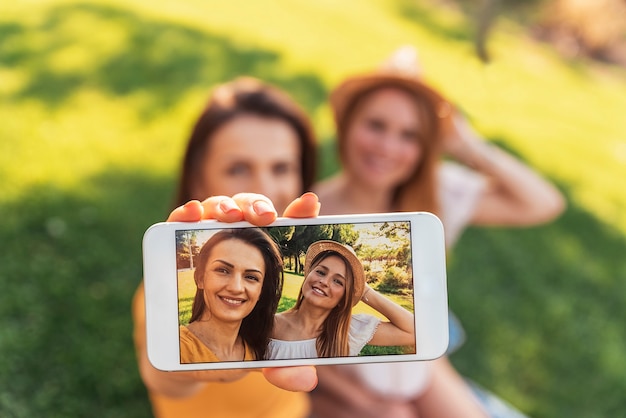 Hermosas mujeres tomando un retrato selfie en el parque. Amigos y concepto de verano.