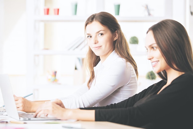 Hermosas mujeres usando laptop en el lugar de trabajo