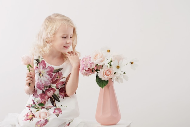 Hermosas niñas rubias con flores sobre fondo blanco