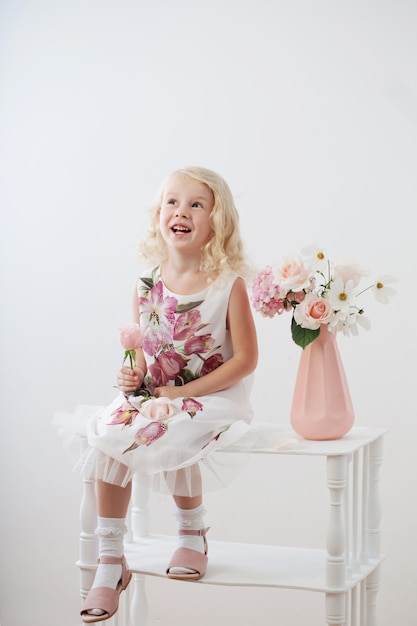 Hermosas niñas rubias con flores sobre fondo blanco