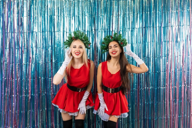 Hermosas novias después de la fiesta. Dos hermosas chicas vestidas con traje de Santa Claus posando sobre un fondo de año nuevo