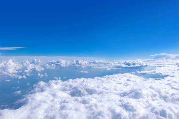 Hermosas nubes blancas mullidas cúmulos en un cielo azul con sol brillante. Fondo de cielo abstracto perfecto, papel tapiz, diseño. Salida del sol sobre las nubes desde la ventana del avión