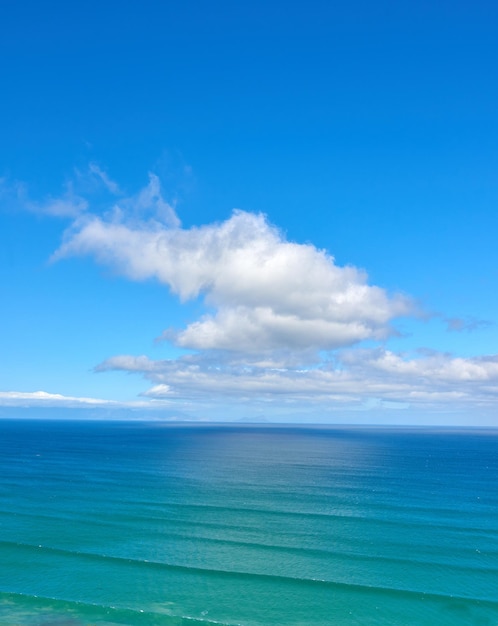 Hermosas nubes cúmulos en un cielo azul sobre un mar azul tranquilo y un océano en verano Magnífica vista panorámica de la playa y el agua azul durante el día Costa idílica y tranquila para unas vacaciones de verano