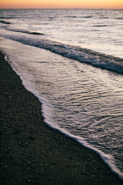 Hermosas olas del mar espuma primer plano y playa de arena con conchas marinas en la luz del amanecer en la isla tropical Olas en el océano al atardecer Tranquilo momento de calma Vacaciones de verano Copiar espacio