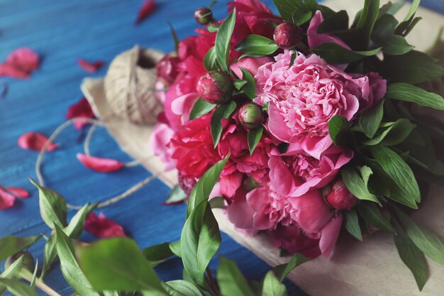 Hermosas peonías y papel de regalo sobre una mesa de madera en una floristería