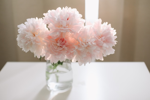 Hermosas peonías rosas en un jarrón en el interior de una casa