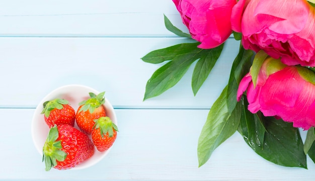 Hermosas peonías y un tazón de fresas.