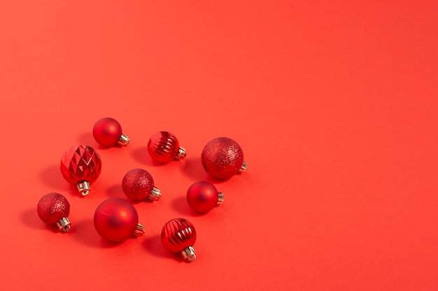 Hermosas pequeñas bolas decorativas rojas se encuentran esparcidas sobre un fondo rojo. Vista superior, endecha plana.