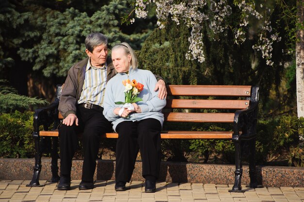 Hermosas personas mayores felices sentados en el parque de otoño.