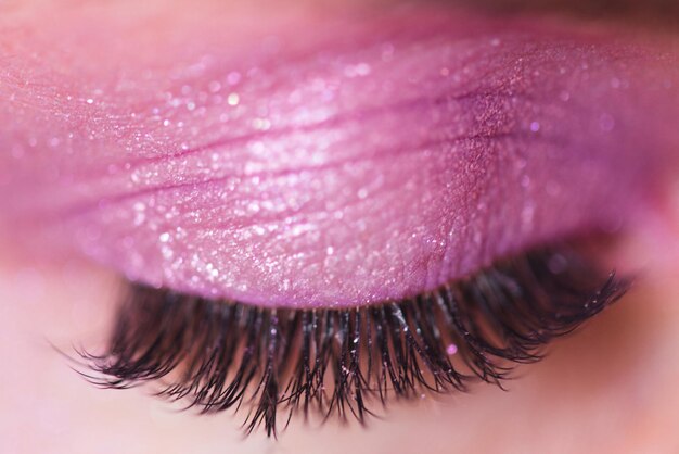 Hermosas pestañas postizas y sombra de ojos rosa en primer plano de párpados cerrados. Enfoque selectivo.