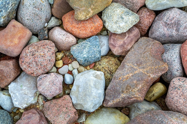 Hermosas piedras de mar pequeñas. Primer plano de guijarros de colores multicolores en una playa.
