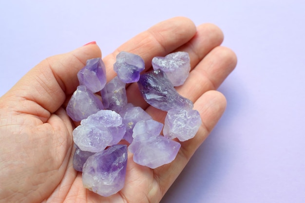 Hermosas piedras semipreciosas en una mano femenina Una mujer sostiene cristales de amatista púrpura en sus manos Piedras mágicas para la meditación
