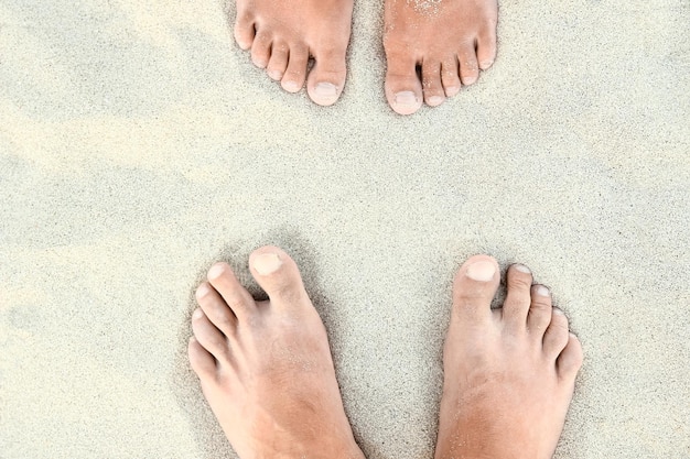 Hermosas piernas en la arena cerca de la orilla del mar en el fondo de la naturaleza